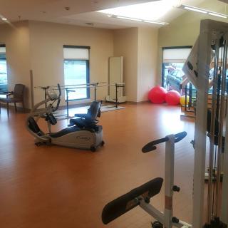 A well-lit gym with various exercise equipment and a spacious workout area.