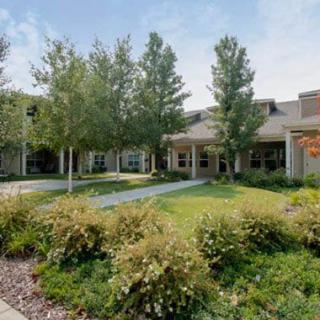 A scenic view of a building surrounded by a landscaped garden with trees and grass.