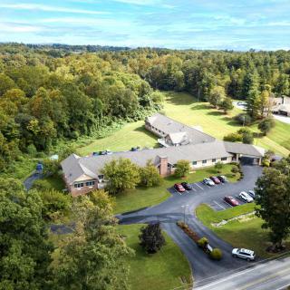 Aerial view of a building surrounded by lush greenery and a parking lot.