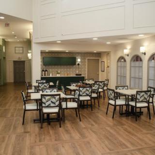 A modern cafe interior with neatly arranged tables and chairs, featuring a bar in the background.