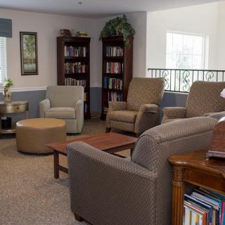 A cozy living room with comfortable chairs, bookshelves, and indoor plants.