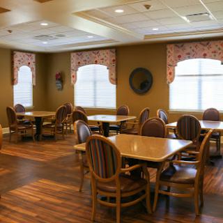 A spacious dining room featuring wooden tables and chairs, with large windows allowing natural light to fill the space.