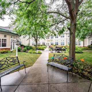 A serene pathway through a well-maintained garden, featuring benches and lush greenery.