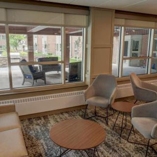 A cozy indoor seating area with modern chairs and tables, overlooking a patio through large windows.
