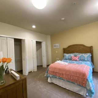A cozy bedroom with a neatly made bed, closet space, and simple decor.