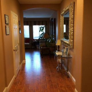 A cozy hallway leading to a warmly lit living room with wooden floors and decorative elements.