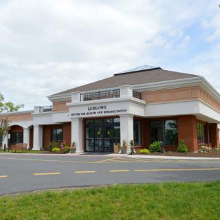 A modern brick commercial building with a main entrance and landscaped surroundings.