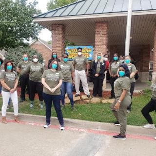 A diverse group of volunteers gathered outside, showcasing teamwork and community spirit while wearing masks for safety.