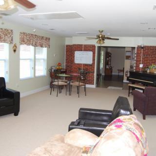 A spacious living room with multiple seating options, a piano, and large windows.