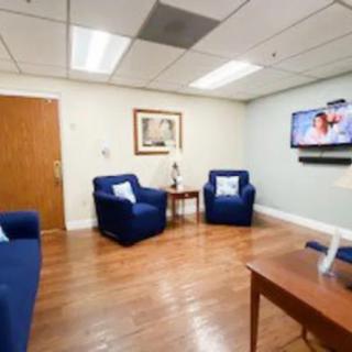 A cozy waiting room with blue chairs, a television, and a wooden floor.
