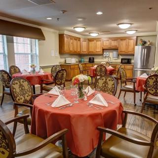 A cozy dining room with decorated tables and a kitchen area in the background.