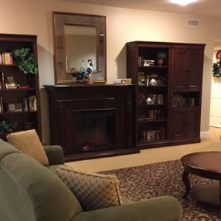 A cozy living room with a fireplace, bookshelves, and comfortable seating.