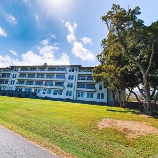 A residential building surrounded by grass and trees under a partly cloudy sky.