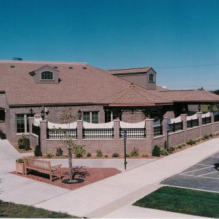 A brick commercial building with a parking lot and sidewalk in front.