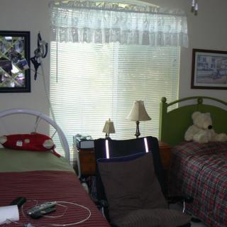 A bedroom with two beds, a stuffed animal, and a window with curtains.