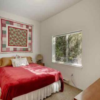 Cozy bedroom with a quilt hanging on the wall and a large window providing natural light.