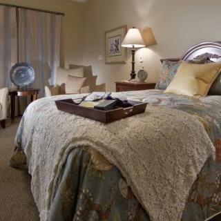 A cozy and elegantly decorated bedroom with a neatly made bed and stylish furnishings.