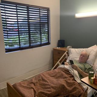 A cozy room with a hospital bed beside a window with blinds.