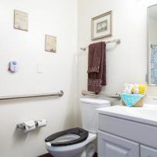 A clean bathroom with accessibility features, including handrails and neatly arranged decor.