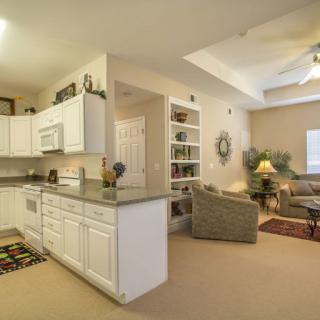 A modern open floor plan featuring a kitchen with white cabinets and an adjacent cozy living room.