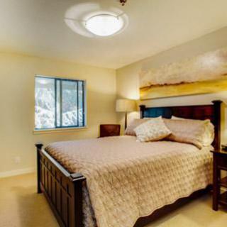 A cozy bedroom with a large bed, bedside lamp, and window.