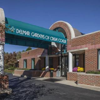 Entrance to a care facility with a green awning and brick exterior.