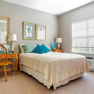 A cozy bedroom with a neatly made bed, decorative pillows, and wooden furniture.