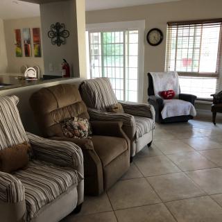 A cozy living room with several armchairs and large windows letting in natural light.