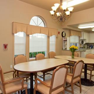 A cozy dining room setup with a table and chairs, adorned with a chandelier and adjacent to a kitchen area.