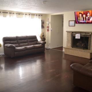 A cozy living room with a sofa, television, and fireplace on wooden flooring.