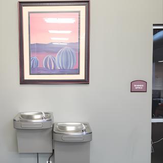 A public area with two water fountains and a framed painting on the wall.
