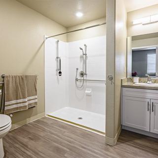 A modern bathroom featuring a spacious shower, toilet, sink with mirror, and neatly arranged towels.