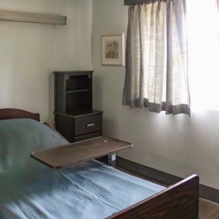 An empty hospital room with a bed and side furniture.