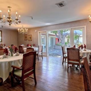 An elegant dining room with chandeliers, set with tables and chairs on a wooden floor.