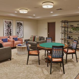 A modern game room with a poker table and comfortable seating area.