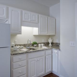 A compact modern kitchen with white cabinets and a granite countertop.