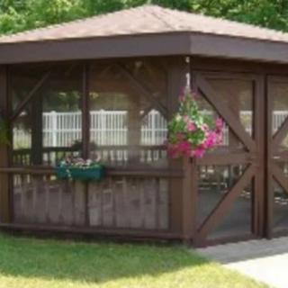A wooden gazebo in a garden setting, adorned with hanging flowers.