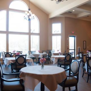 A bright and spacious restaurant dining area with elegantly set tables and chairs.