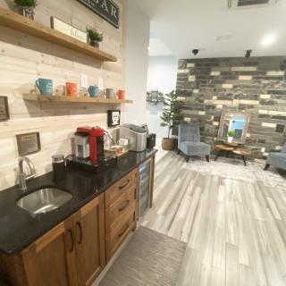 A cozy kitchenette with a modern relaxation area featuring wooden accents and a coffee station.
