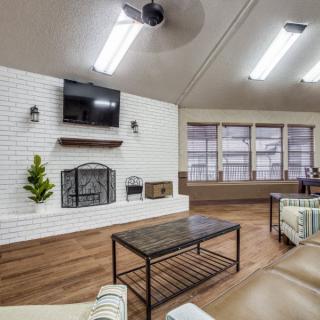 A modern living room featuring a brick fireplace, mounted television, and wooden flooring.