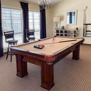 A stylish game room featuring a pool table with cue sticks and balls neatly arranged on top.
