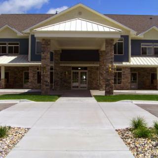 A welcoming entrance to a modern residential building, featuring well-maintained landscaping and a spacious walkway.