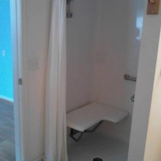 Accessible shower with a seat and curtain.