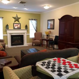 A cozy living room featuring a fireplace, comfortable seating, and a checkerboard game setup.
