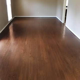 An empty room with sleek hardwood flooring and natural light streaming in.