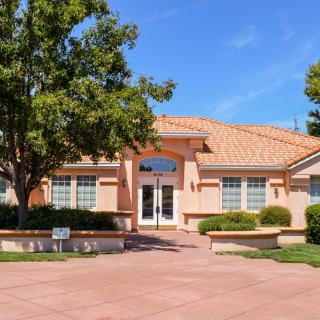 A suburban house with a landscaped front yard and a wide driveway on a sunny day.