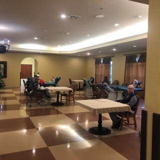 A spacious activity room designed for seniors, featuring tables and chairs arranged for social interaction.
