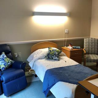 A cozy hospital room with a single bed, chairs, and a small table.