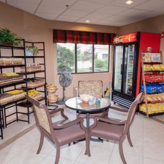 A snack area with tables and chairs, featuring shelves stocked with snacks and a refrigerator.