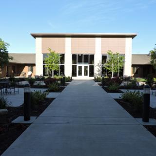 A modern building entrance with a landscaped walkway and trees.